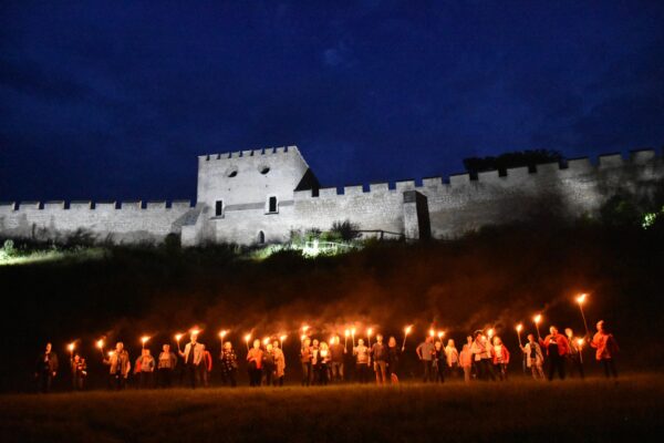 Nocne zwiedzanie Szydłowa, mury obronne, ludzie z pochodniami, oświetlony zamek