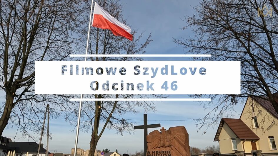 Biało-czerwona flaga na maszcie pośród drzew bez liści, pomnik z krzyżem, napis Filmowe SzydLove Odcinek 46